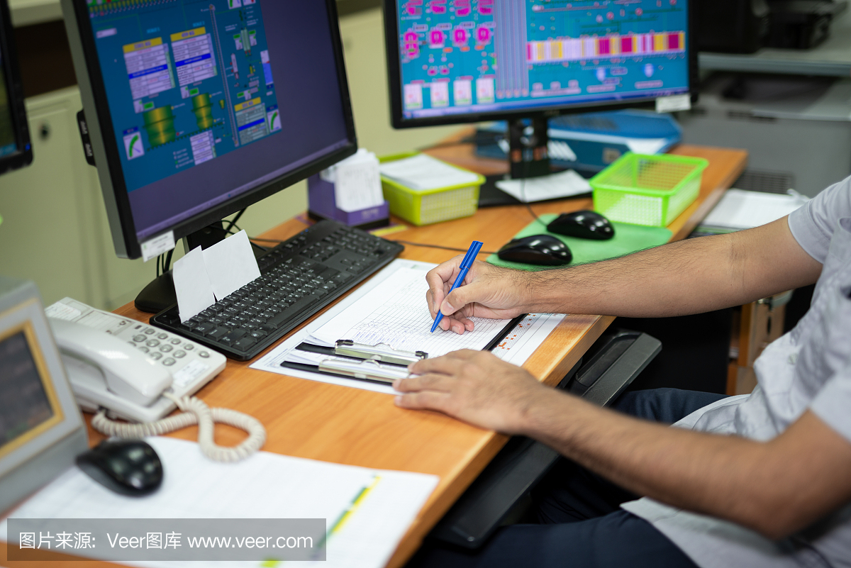 男员工在生产控制室写笔记工作。饲料加工厂的机器由一台计算机控制